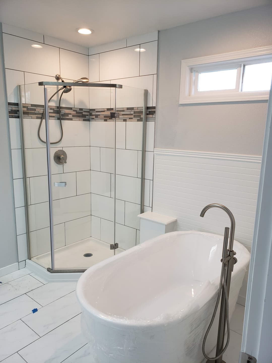 remodeled bathroom with white tiling and new white luxury bathtub